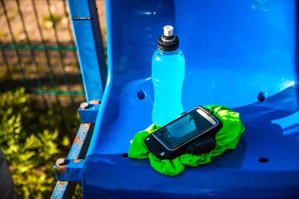 Fondo físico. una botella de agua en el podio de fútbol con teléfono inteligente y camiseta mojada —  Fotos de Stock