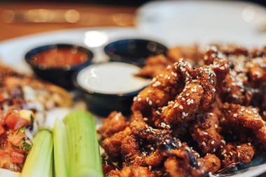 dilimlenmiş tavuk göğsü kotletpane ve derin kızarmış tavuk parçaları, susam, krem ve domates sosu serpilir, teriyaki sosu, kereviz kök bir plaka üzerinde sebzeli pizza dilimleri.