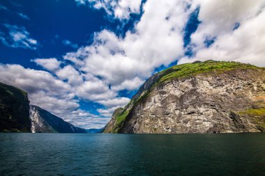 Dağlar ve Norveç'te fiyort. Mavi gökyüzü ve bulutlar. Dağlar, su, gökyüzü, bulutlar ve güneş manzarası çok güzel. Norveç doğa