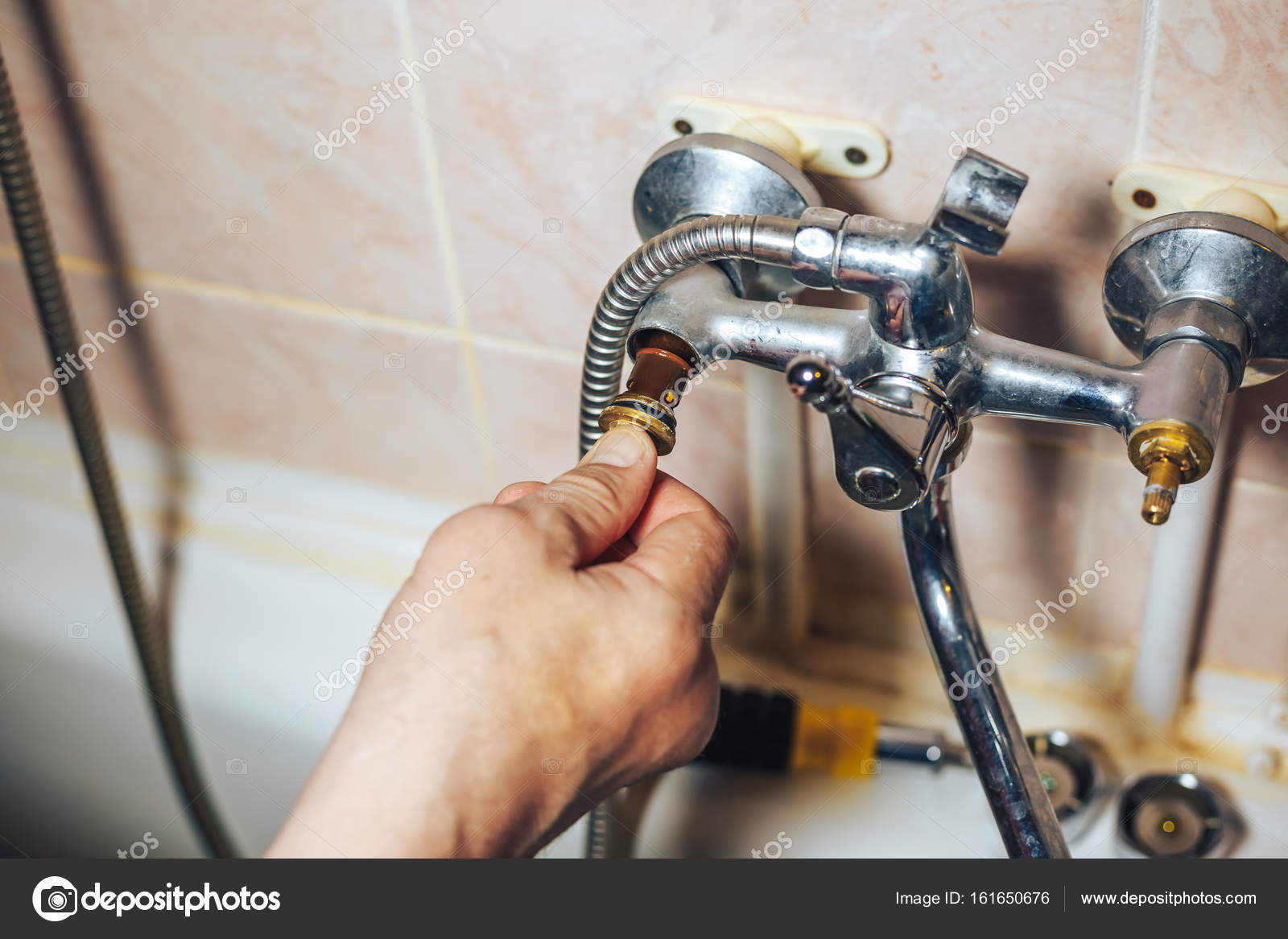 Man Repair And Fixing Leaky Old Faucet In Bathroom Stock Photo