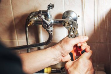 Man repair and fixing leaky old faucet in bathroom clipart