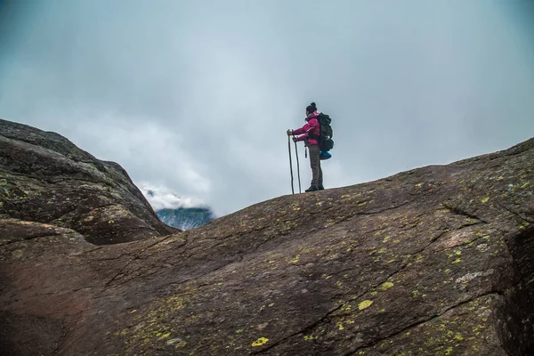 Dívka stojí na vrcholu pískovcové skály. Krásné chvíle zázrak přírody. Ranní horské pozadí. Dívka hodinky mlhavé zázrak. Trolltunga turistické trasy — Stock fotografie