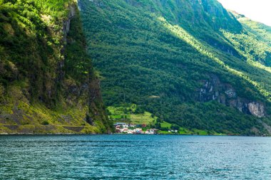 Flam Fjords, Norveç, güzel bir zemin ile küçük bir köy. Dağlar ve Norveç'te fiyort. Mavi gökyüzü ve bulutlar. Dağlar, su, gökyüzü, bulutlar ve güneş manzarası çok güzel. Norveç doğa.