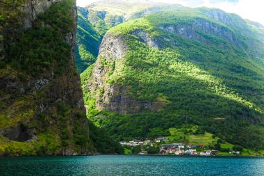 Flam Fjords, Norveç, güzel bir zemin ile küçük bir köy. Dağlar ve Norveç'te fiyort. Mavi gökyüzü ve bulutlar. Dağlar, su, gökyüzü, bulutlar ve güneş manzarası çok güzel. Norveç doğa.
