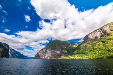 Dağlar ve Norveç'te fiyort. Mavi gökyüzü ve bulutlar. Dağlar, su, gökyüzü, bulutlar ve güneş manzarası çok güzel. Norveç doğa