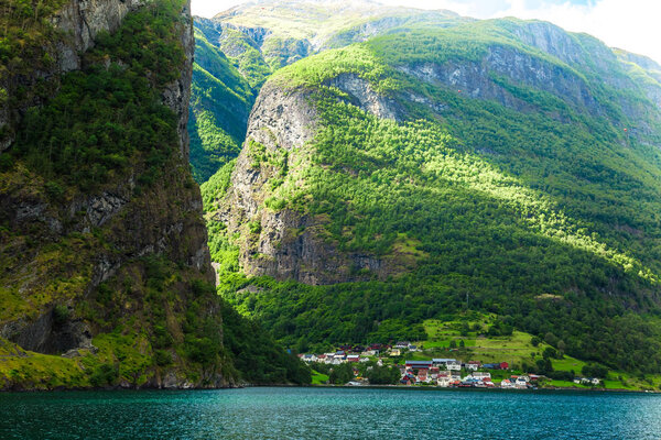 Небольшая деревушка с прекрасным обратным откосом на Флам-фьордах, Норвегия. Горы и фьорды в Норвегии. Облака и голубое небо. Потрясающий вид на горы, воду, небо, облака и солнце. Природа Норвегии
.