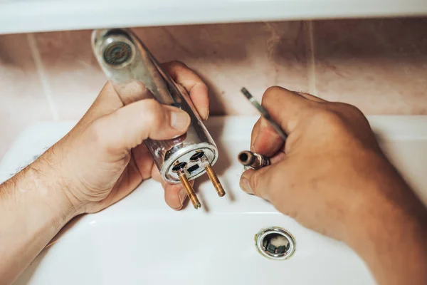 Servizi uomo e riparazioni vecchio rubinetto che perde sul rubinetto in bagno. L'uomo svita il vecchio miscelatore — Foto Stock