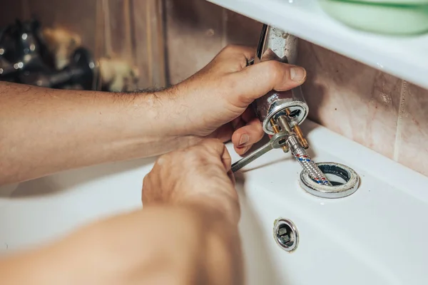 Man services and repairs leaky old faucet on the tap in the bathroom — Stock Photo, Image