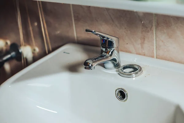 Hombre reparación y fijación de fugas grifo viejo en el baño. El hombre desempaquetó el nuevo grifo y se preparó para su instalación — Foto de Stock