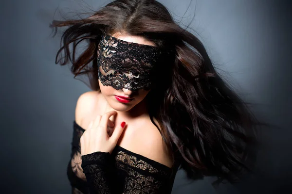 Siyah arka plan üzerine siyah iç çamaşırı seksi kız. Erotik photoshoot göz bağını maskesi yüzünde çekici kadın büyüleyici. Havada uçan kızın saçları