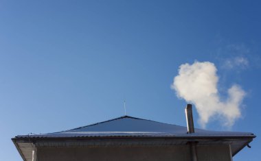 duman ev bacadan geliyor. Mavi gökyüzü arka plan