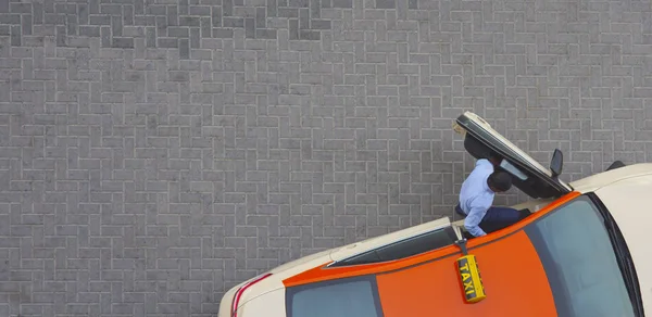 business man enter the taxi in city. background of tile stones in the street