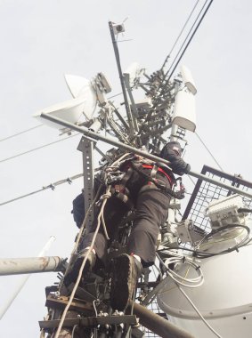 Elektrikçi adam anten onarmak için direğe tırmanıyor.