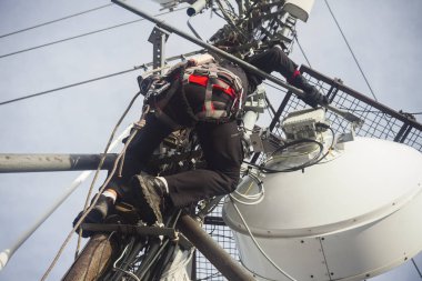 Elektrikçi adam anten onarmak için direğe tırmanıyor.