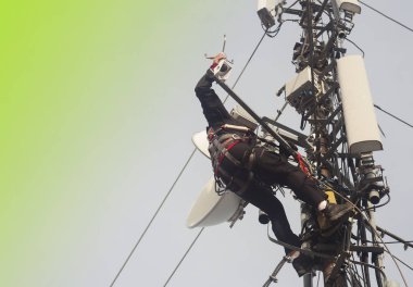 Elektrikçi ya da dağcı teftiş için direk antenine tırmanıyor. Metnin için soyut yeşil arkaplan
