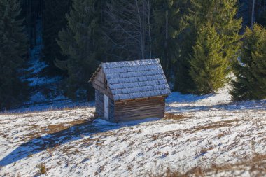 Kışın dağ manzarasında eski bir kır kulübesi. Romanya