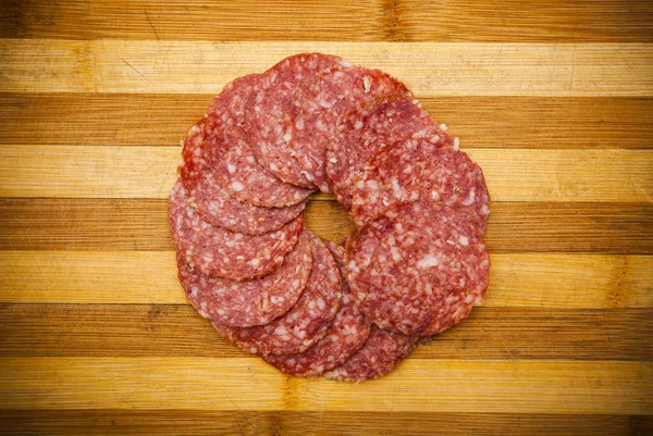 腊肠或腊肠肉片放在切菜板上的圆圈里 — 图库照片