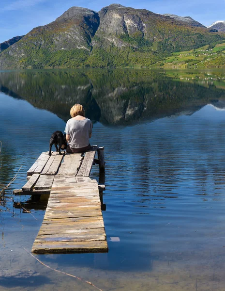 Жінка з собакою сидить на мосту — стокове фото