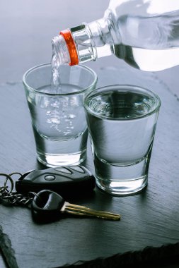 Bardaklara ve araba anahtarlarına alkol dökülüyor. 