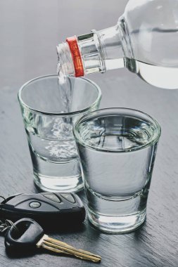 Bardaklara ve araba anahtarlarına alkol dökülüyor. 