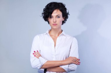 Mutlu genç esmer gri arka plan kopya alanı arıyor çapraz silah ile kamera ile işkadını kıvırcık saç