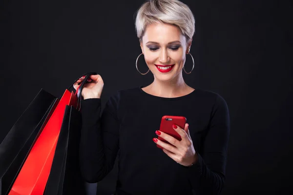 Shopping kvinna som håller färgen väskor isolerad på blå bakgrund i svart fredag semester. Sommar försäljning koncept. — Stockfoto