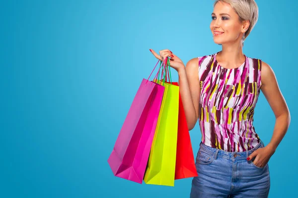 Mujer de compras sosteniendo bolsas de color aisladas sobre fondo azul en vacaciones de viernes negro. Concepto de venta verano . —  Fotos de Stock