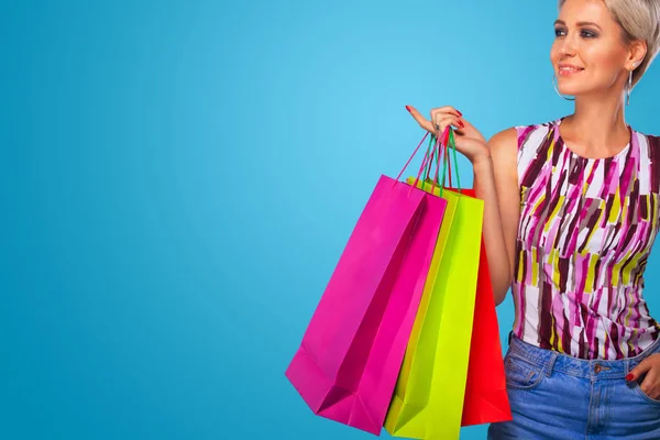 Shopping kvinna som håller färgen väskor isolerad på blå bakgrund i svart fredag semester. Sommar försäljning koncept. — Stockfoto