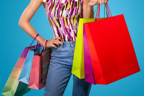 Shopping kvinna som håller färgen väskor isolerad på blå bakgrund i svart fredag semester. Sommar försäljning koncept. — Stockfoto