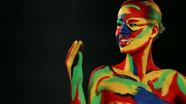 Mulher com arte facial colorida e pintura corporal. Menina com maquiagem colorida brilhante e bodyart apontando para a direita — Vídeo de Stock