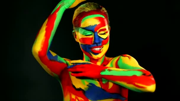 Kobieta tańczy z kolorową sztuką twarzy i farbą do ciała. Kolorowy portret dziewczyny z jasnym makijażem i body art. — Wideo stockowe