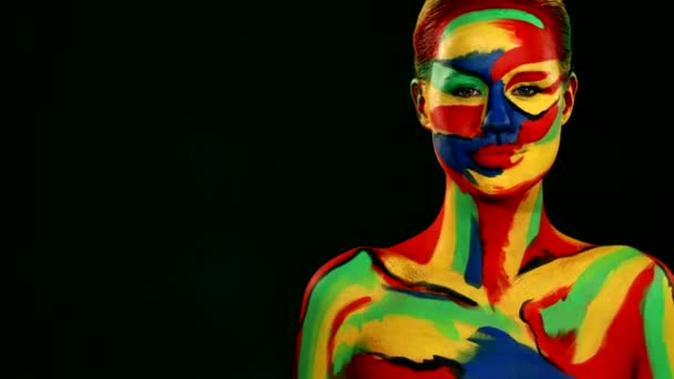 Vrouw met kleur gezicht kunst en body paint. Meisje met heldere kleurrijke make-up en bodyart wijzen naar rechts — Stockvideo
