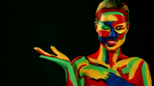 Kobieta z kolorowym malowaniem twarzy i ciała. Dziewczyna z jasnym kolorowy makijaż i bodyart wskazując na patrząc w prawo — Wideo stockowe