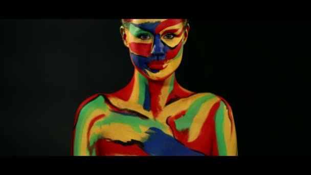 Жінка з кольоровим мистецтвом обличчя та фарбою для тіла. Барвистий портрет дівчини з яскравим макіяжем і бодіарт . — стокове відео