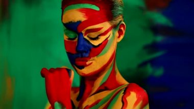 Renkli yüz ve vücut boyalı bir kadın. Parlak makyajlı ve vücut destekli kızın renkli portresi..