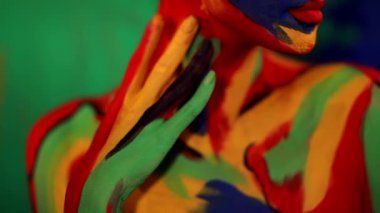 Renkli yüz ve vücut boyalı bir kadın. Parlak makyajlı ve vücut destekli kızın renkli portresi..