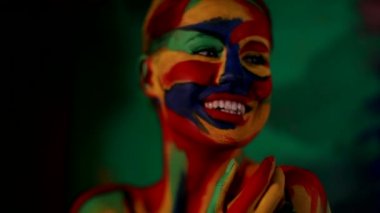 Renkli yüz ve vücut boyalı bir kadın. Parlak makyajlı ve vücut destekli kızın renkli portresi..