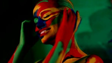 Renkli yüz ve vücut boyalı bir kadın. Parlak makyajlı ve vücut destekli kızın renkli portresi..