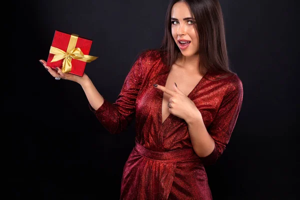 Sorpresa el día de San Valentín y el Día Internacional de la Mujer. Joven mujer feliz con un regalo rojo sobre fondo negro . —  Fotos de Stock