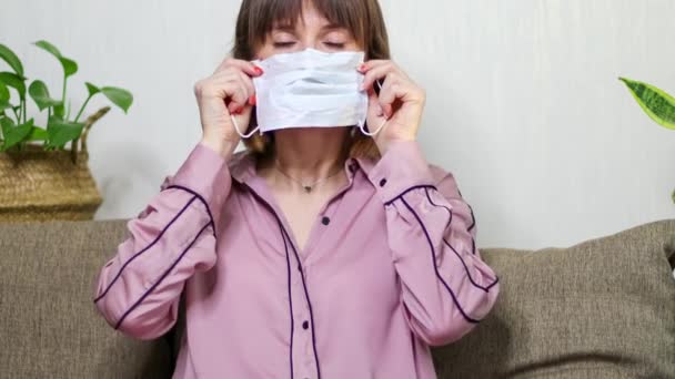 Оставайся дома и спаси планету. Женщина надевает медицинскую маску на лицо. Здравоохранение Контроль коронавируса в 4k — стоковое видео