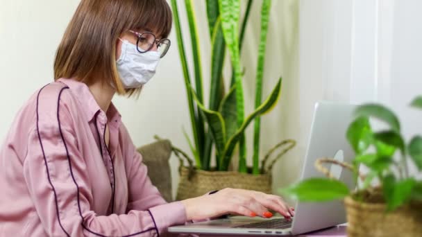 Zastavte koronavirus. Zůstaň doma a zachraň planetu. Děvče pracuje na laptopu. Žena v lékařské masce má online konferenci — Stock video