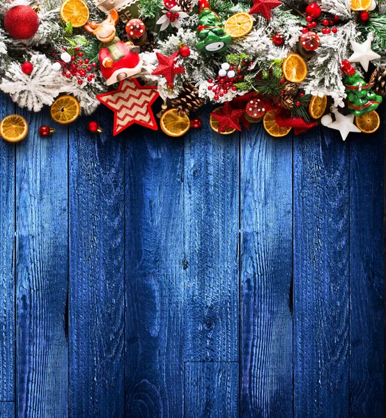Χαρούμενα Χριστούγεννα πλαίσιο με το πράσινο των πεύκων, πολύχρωμα στολίδια και ξύλινο υπόβαθρο — Φωτογραφία Αρχείου