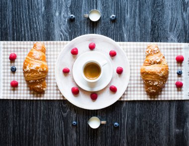 Ahşap bir masa üstten görünüm fincan kahve, kruvasan, taze çilek ile