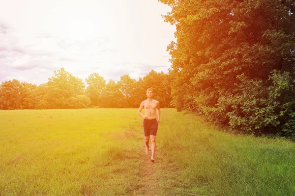 Jeune homme déshabillé courant dans un paysage avec une forte lumière . — Photo