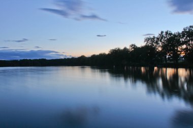 Günbatımı ağaçlar siluet ve turuncu gökyüzü, uzun exposu gölet üzerinde
