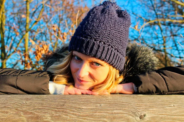 Beautiful young woman with cap lean on wood — Stock Photo, Image