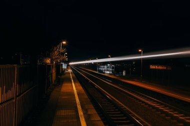 Açık renkli tren rayları gece istasyonda, hava manzaralı. Trafik, seyahat, uzun pozlu fotoğraf.