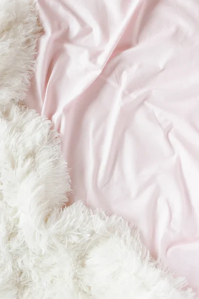 Pale pink linens and white fluffy blanket