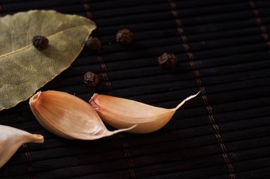 sarımsak, defne yaprağı ve siyah bir zemin üzerine karabiber