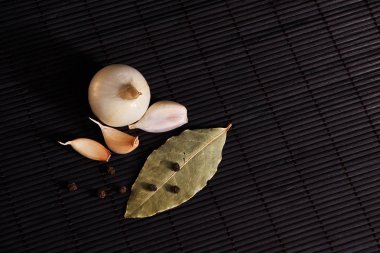 Defne yaprağı, soğan ve sarımsak siyah masa üstü. Kuru baharat karışımı
